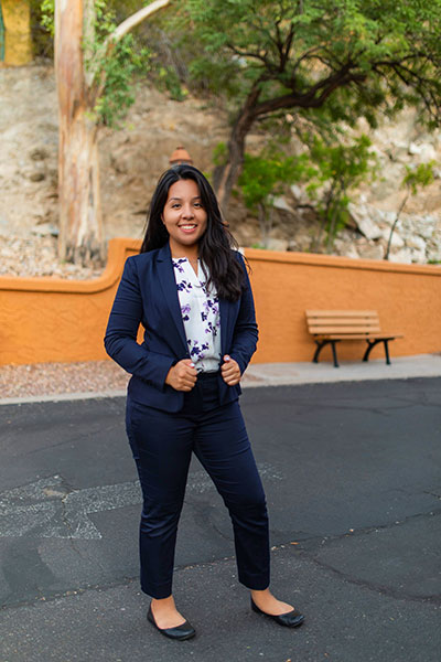 Ximena Perez standing outside in a navy blue suit, facing the camera. 