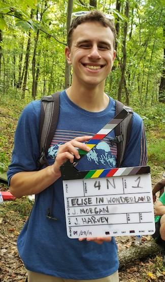 Joshua in the woods with a film slate