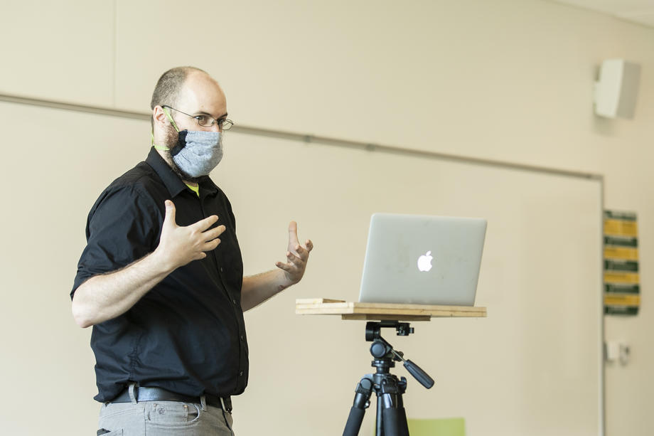 Man gesturing with both hands in front of laptop on a tripod