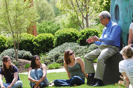 Roger Wilkins talks with Mason students outside in spring